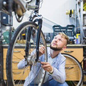 male-bicycle-mechanic-repairing-bicycle-tire-shop